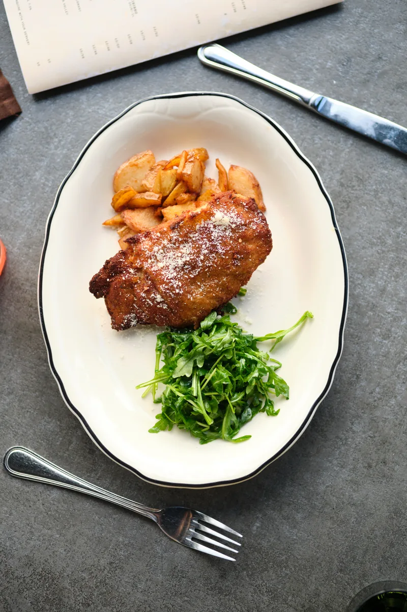 A browned main-course plate with potatoes and leafy greens at Civico 1845