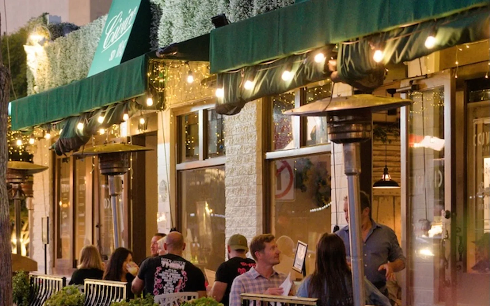 Diners seated on Civico 1845's heated outdoor patio beneath green awnings