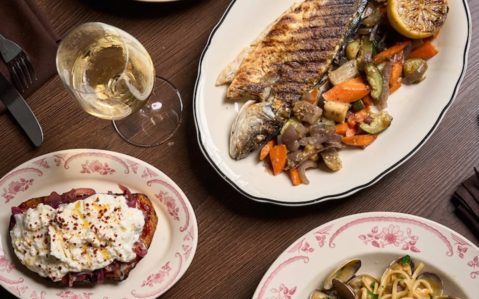 Civico 1845 table spread with grilled fish, pasta, crostini and white wine